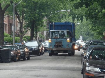 A blue colored dump truck moving on the road